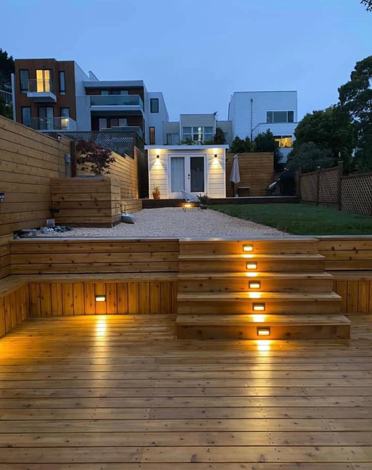 Completed custom multi-level wood deck with integrated stair lighting, retaining walls, outdoor living space, and backyard renovation in Oakland, California.