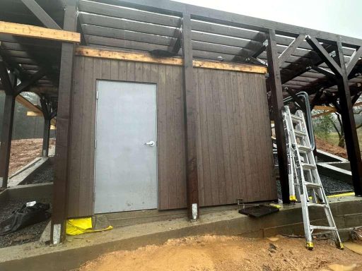 Completed wood structure with exterior siding and door on hillside construction project