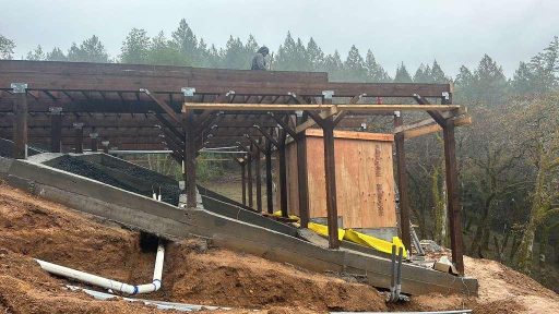 Wood structure framing on hillside with concrete foundation and drainage system under construction in Sonoma County