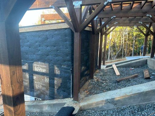 Wood framing structure with waterproofing barrier and concrete foundation on hillside construction project